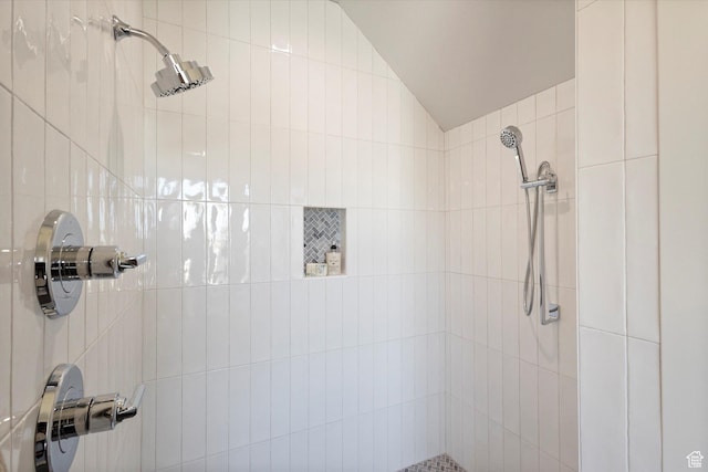 bathroom with tiled shower and vaulted ceiling