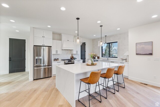 kitchen featuring light countertops, stainless steel appliances, a center island, and premium range hood