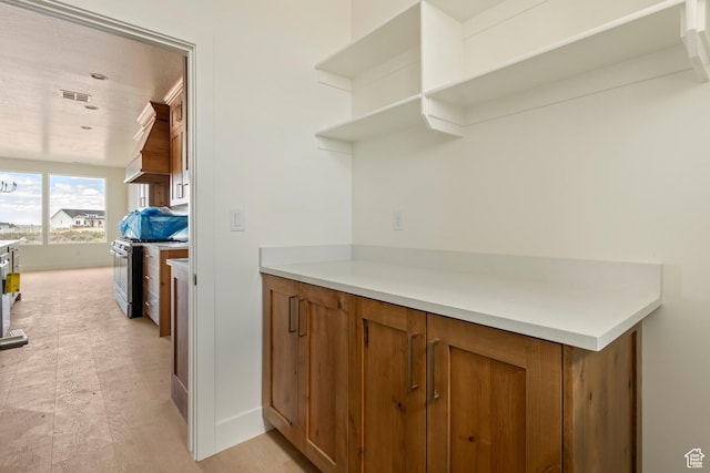 4416 W 1900 S, Cedar City, UT 84720 - kitchen featuring open shelves, brown cabinets, stainless steel range with gas cooktop, light countertops, and baseboards