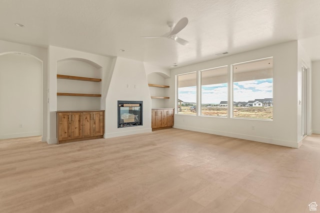4416 W 1900 S, Cedar City, UT 84720 - unfurnished living room featuring ceiling fan, baseboards, built in shelves, and a glass covered fireplace