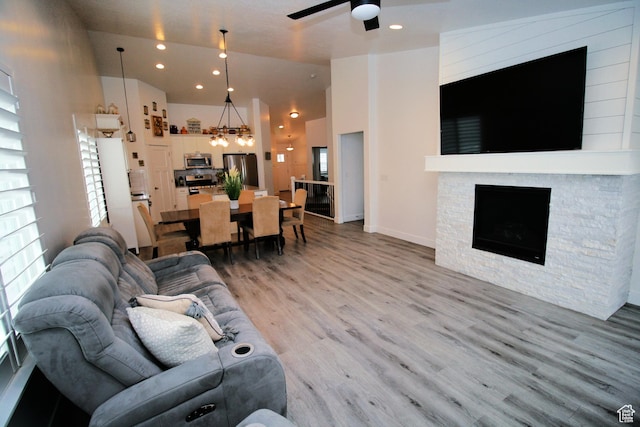 13207 S Weatherford Ln W, Herriman, UT 84096 - living room featuring a stone fireplace, ceiling fan with notable chandelier, light wood-style floors, and recessed lighting