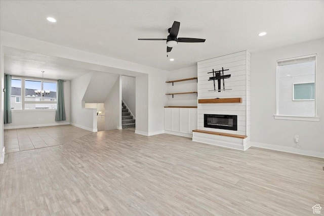 13192 S Lowick Ln, Herriman, UT 84096 - unfurnished living room with baseboards, stairs, a fireplace, and light wood finished floors