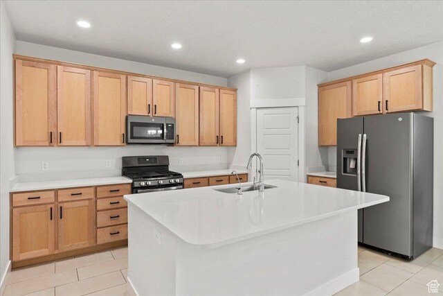 13192 S Lowick Ln, Herriman, UT 84096 - kitchen featuring light tile patterned floors, a sink, a kitchen island with sink, and appliances with stainless steel finishes