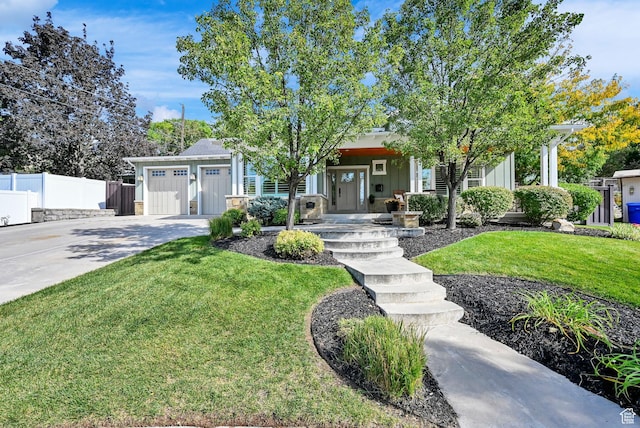view of front of property featuring a front yard, concrete driveway, fence, board and batten siding, and a garage