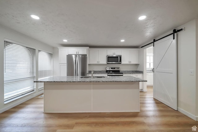 4195 W Kirkcaldy Cir S, South Jordan, UT 84009 - kitchen with white cabinets, light wood-style floors, a center island with sink, appliances with stainless steel finishes, and a sink