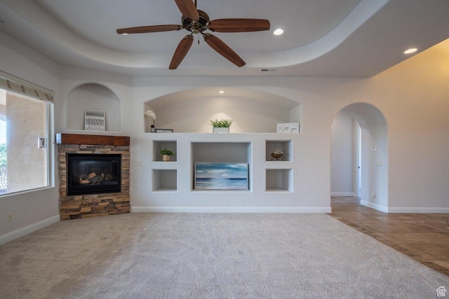 2104 S Corral Way, Washington, UT 84780 - unfurnished living room featuring carpet flooring, a stone fireplace, a tray ceiling, and built in shelves