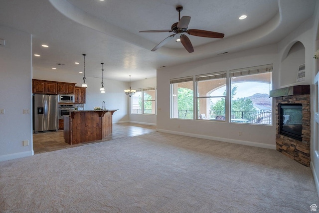 2104 S Corral Way, Washington, UT 84780 - kitchen with open floor plan, light colored carpet, a raised ceiling, a stone fireplace, and appliances with stainless steel finishes