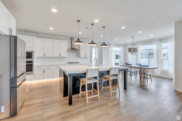 1031 S 950 W, American Fork, UT 84003 - kitchen featuring appliances with stainless steel finishes, wall chimney exhaust hood, a sink, light countertops, and an island with sink