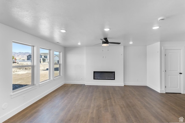 3205 N 3500 W Unit 378, Plain City, UT 84404 - unfurnished living room featuring dark wood-type flooring, ceiling fan, baseboards, and a glass covered fireplace