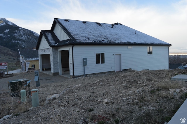 back of property featuring a shingled roof, a garage, and a mountain view