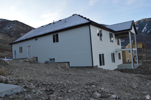 rear view of house featuring a shingled roof, a mountain view, and a patio area