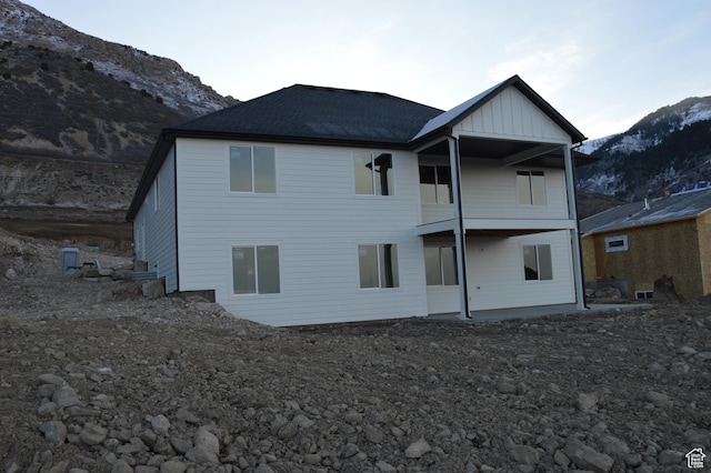 back of house with board and batten siding, a mountain view, and roof with shingles