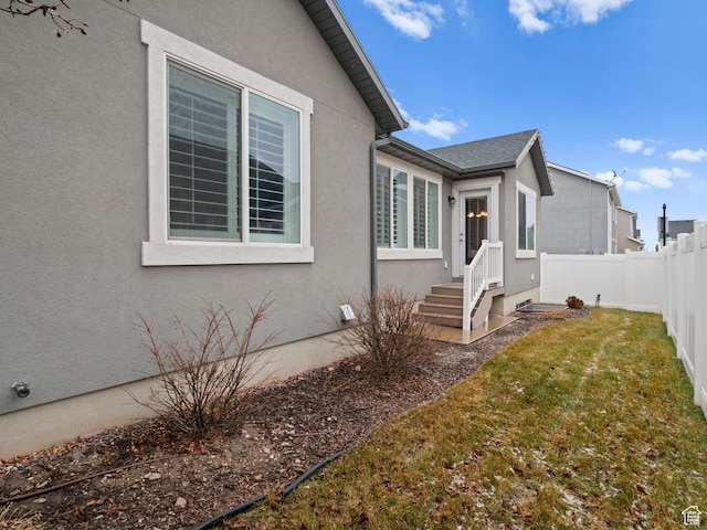 4981 W Longboat Ln, Herriman, UT 84096 - view of home's exterior featuring stucco siding, a shingled roof, fence, and a lawn