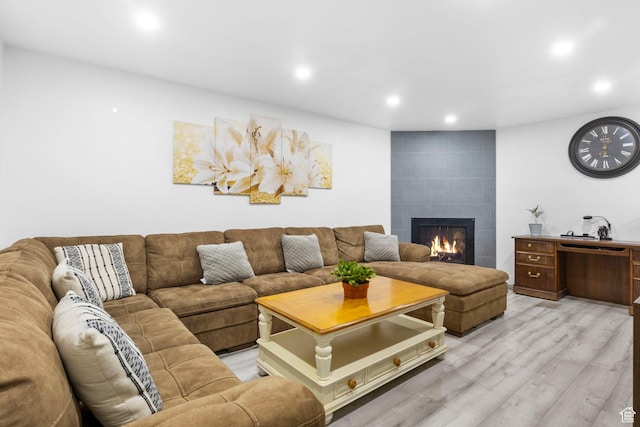 living area featuring a tiled fireplace, light wood-type flooring, and recessed lighting