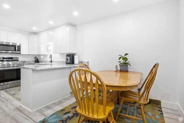314 W Center St Unit F118, Bountiful, UT 84010 - kitchen with light wood-style flooring, white cabinetry, light stone countertops, and stainless steel appliances