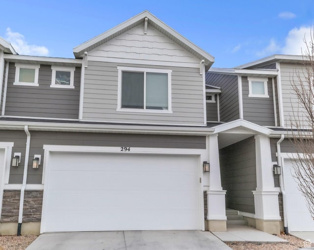 view of front of house featuring stone siding, concrete driveway, and a garage