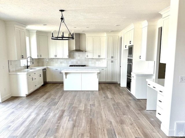 2873 E Liam Ln Unit 105, Eagle Mountain, UT 84005 - kitchen with wall chimney exhaust hood, light wood-type flooring, decorative backsplash, light countertops, and a textured ceiling
