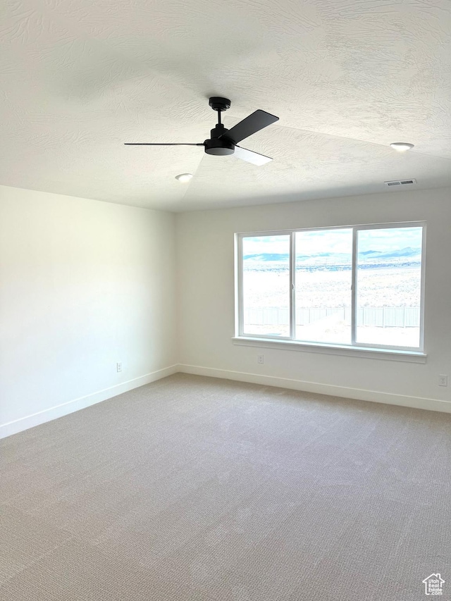 empty room with light colored carpet, visible vents, ceiling fan, and baseboards