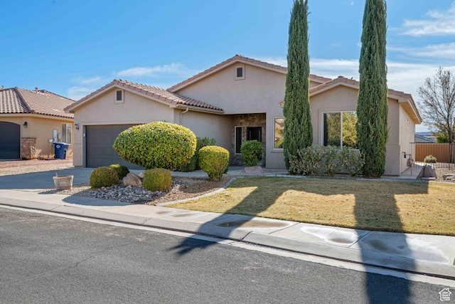 mediterranean / spanish house with a tile roof, concrete driveway, stucco siding, and fence
