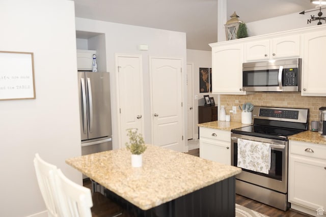 1751 E 1130 S, Spanish Fork, UT 84660 - kitchen featuring appliances with stainless steel finishes, white cabinets, decorative backsplash, light stone countertops, and a kitchen island