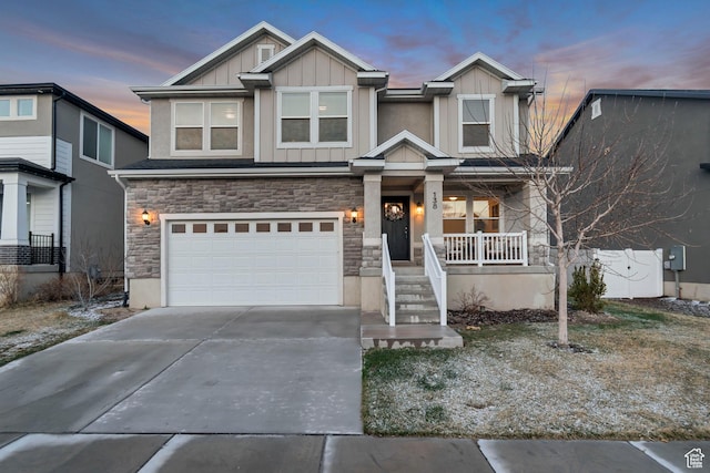 138 N Valcrest Dr, Saratoga Springs, UT 84045 - view of front facade featuring driveway, covered porch, stone siding, an attached garage, and board and batten siding