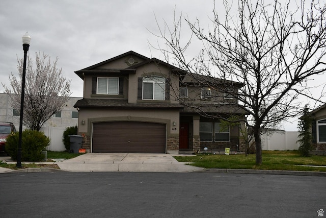 traditional-style house featuring stone siding, an attached garage, concrete driveway, a front lawn, and stucco siding