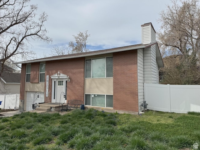 view of front facade with an attached garage, brick siding, fence, and a chimney