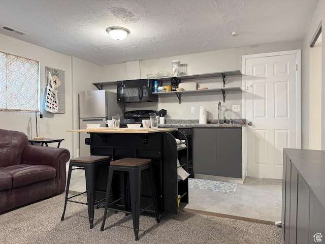 95 E Continental Dr S Unit 61-G, Farmington, UT 84025 - kitchen with open shelves, a textured ceiling, visible vents, freestanding refrigerator, and black microwave