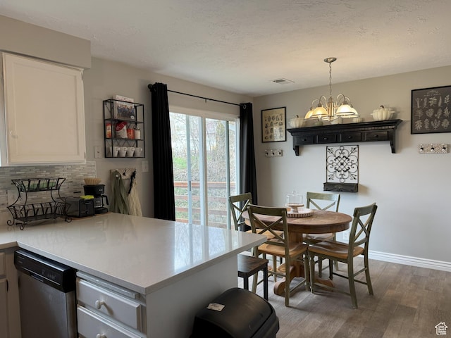 95 E Continental Dr S Unit 61-G, Farmington, UT 84025 - kitchen with light countertops, a peninsula, wood finished floors, stainless steel dishwasher, and a notable chandelier