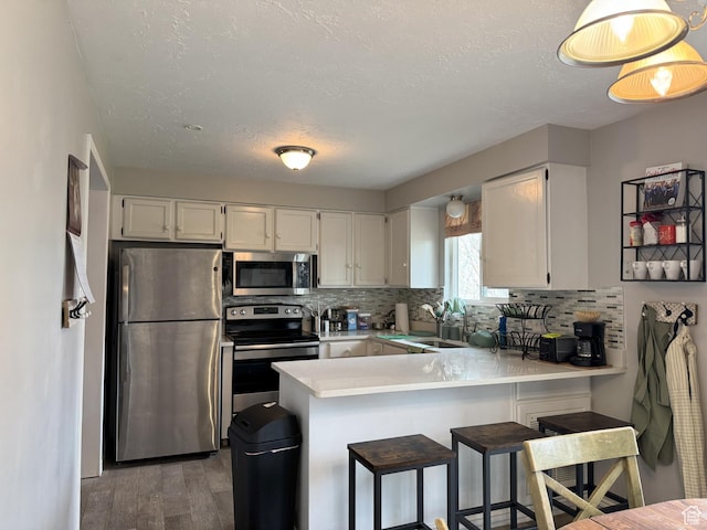 95 E Continental Dr S Unit 61-G, Farmington, UT 84025 - kitchen featuring light countertops, stainless steel appliances, backsplash, a sink, and a peninsula