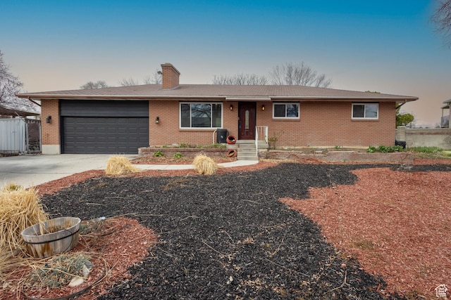 single story home with a chimney, a garage, concrete driveway, and brick siding