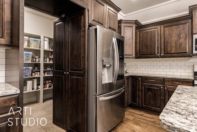 2691 E 3800 S, St George, UT 84790 - kitchen featuring stainless steel refrigerator with ice dispenser, decorative backsplash, light wood-style floors, light stone counters, and dark brown cabinets