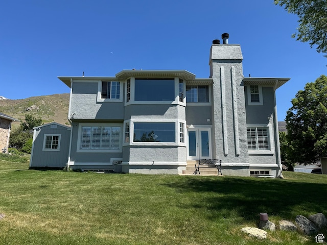 back of house with french doors, a mountain view, stucco siding, and a yard