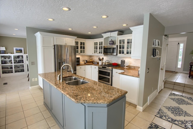 kitchen featuring light tile patterned floors, appliances with stainless steel finishes, a center island with sink, and a sink