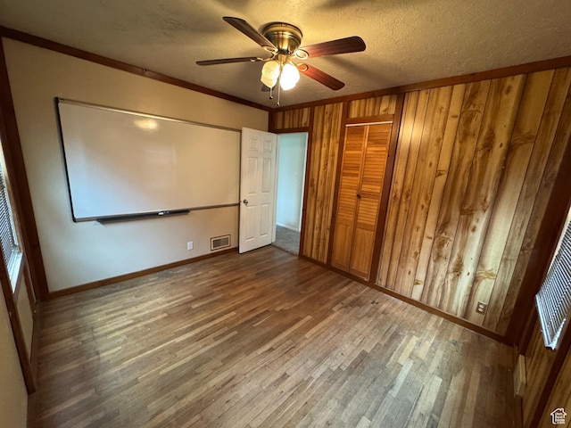 26 Sylvia Dr N, South Ogden, UT 84405 - unfurnished bedroom featuring visible vents, baseboards, a textured ceiling, wooden walls, and wood finished floors