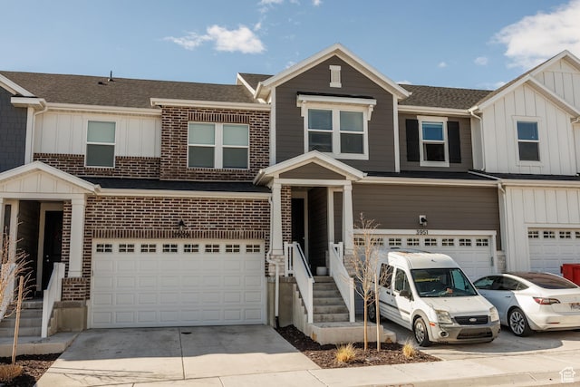 multi unit property featuring brick siding, a garage, board and batten siding, and concrete driveway