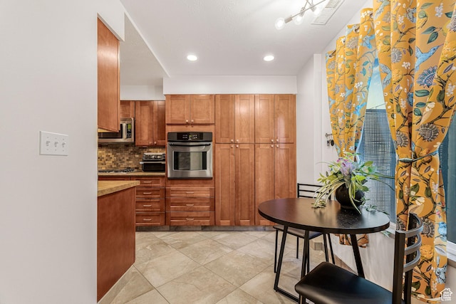4667 S Black Swan Dr, Millcreek, UT 84117 - kitchen with brown cabinetry, tasteful backsplash, visible vents, recessed lighting, and appliances with stainless steel finishes