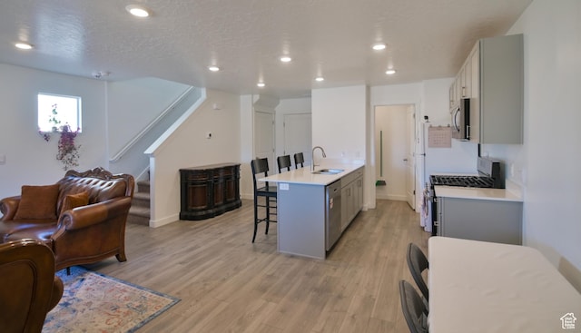 1088 E Propeller Row, Saratoga Springs, UT 84045 - kitchen featuring a kitchen breakfast bar, open floor plan, gray cabinetry, a sink, and appliances with stainless steel finishes