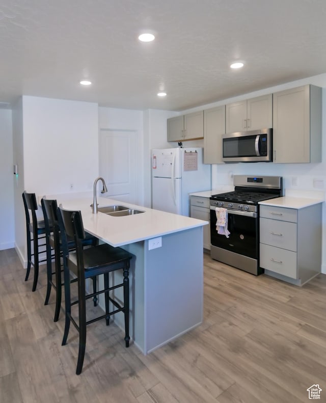 1088 E Propeller Row, Saratoga Springs, UT 84045 - kitchen with a kitchen breakfast bar, gray cabinets, a sink, light wood finished floors, and appliances with stainless steel finishes