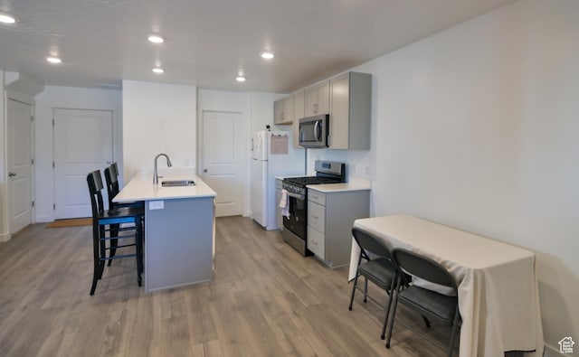 1088 E Propeller Row, Saratoga Springs, UT 84045 - kitchen with a sink, light wood finished floors, a kitchen breakfast bar, appliances with stainless steel finishes, and gray cabinetry