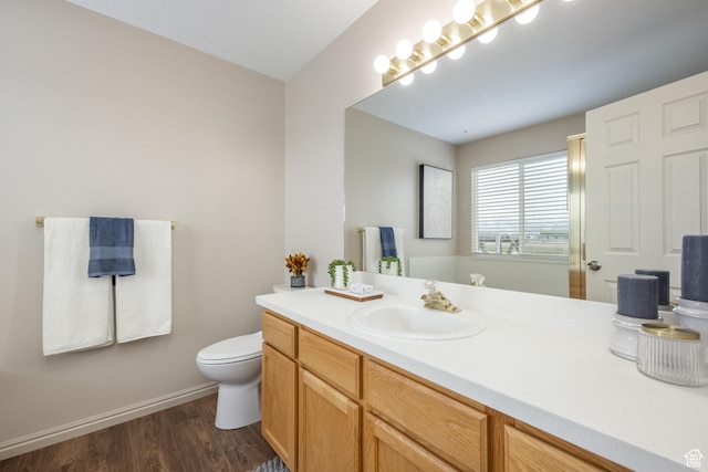 bathroom with baseboards, wood finished floors, toilet, and vanity