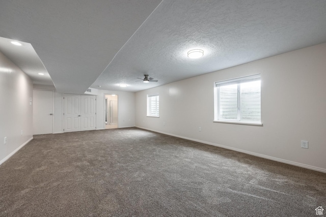 basement with carpet, a textured ceiling, a ceiling fan, and baseboards