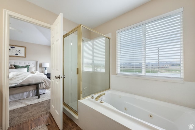 ensuite bathroom featuring connected bathroom, a jetted tub, wood finished floors, and plenty of natural light