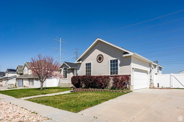 view of front of house with an attached garage, driveway, fence, and a front yard