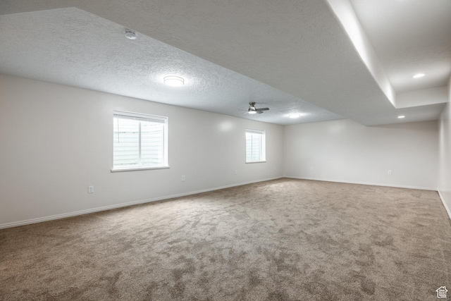 below grade area featuring baseboards, a ceiling fan, a textured ceiling, and carpet floors