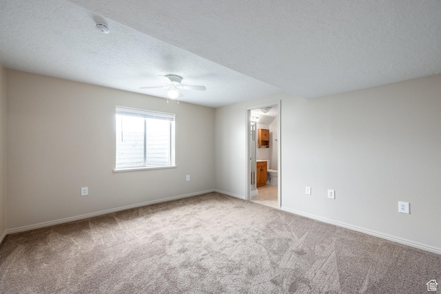 empty room featuring light carpet, baseboards, and ceiling fan