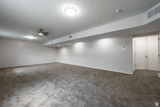finished below grade area featuring carpet flooring, a textured ceiling, visible vents, baseboards, and ceiling fan
