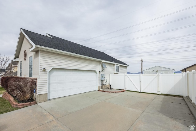 view of side of property with a gate, driveway, a garage, and fence