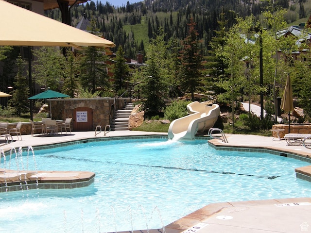 12080 E Big Cottonwood Rd Unit 214, Brighton, UT 84121 - community pool featuring stairs, a water slide, a view of trees, and a patio