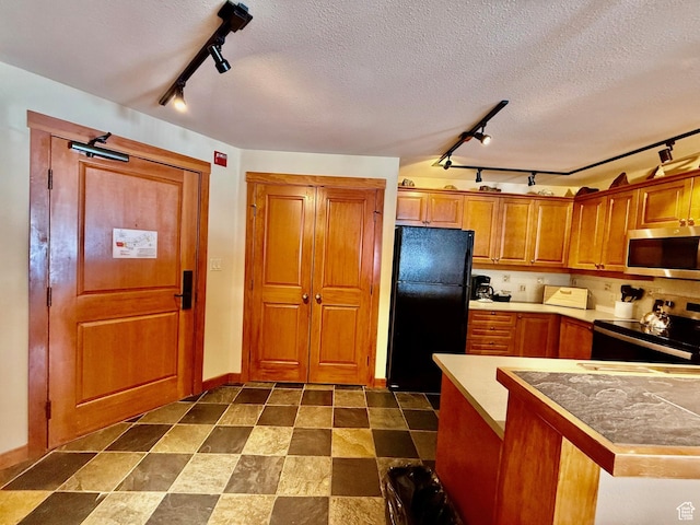12080 E Big Cottonwood Rd Unit 214, Brighton, UT 84121 - kitchen featuring track lighting, stainless steel appliances, brown cabinets, baseboards, and a textured ceiling